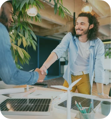 Imagem de um homem no canto esquerdo da tela de camisa social apertando a mão de um homem vestido de camisa social também enquanto sorri